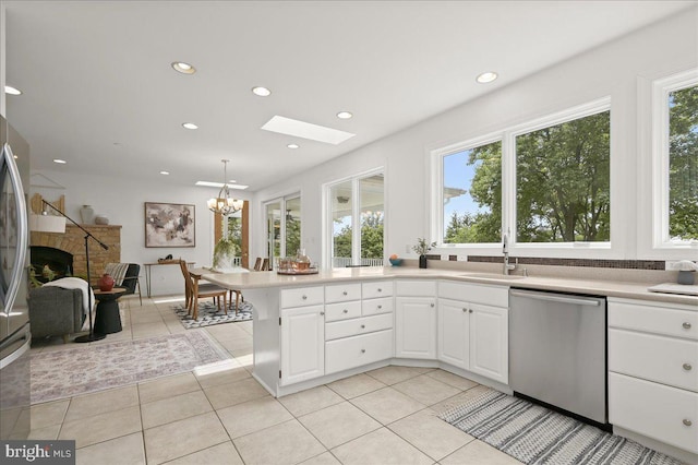 kitchen featuring a fireplace, light countertops, a sink, and stainless steel dishwasher