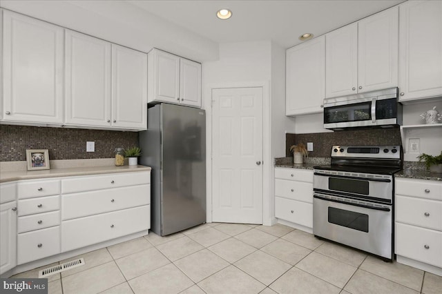 kitchen with white cabinets, visible vents, stainless steel appliances, and backsplash