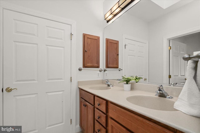 bathroom featuring double vanity, a skylight, and a sink