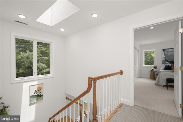 hallway with a skylight, visible vents, carpet, an upstairs landing, and recessed lighting