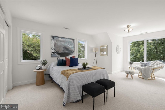 bedroom featuring light carpet, multiple windows, visible vents, and baseboards