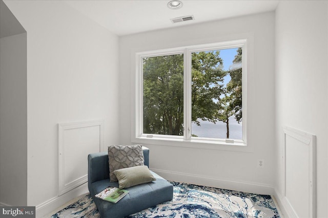 living area with a healthy amount of sunlight, baseboards, and visible vents