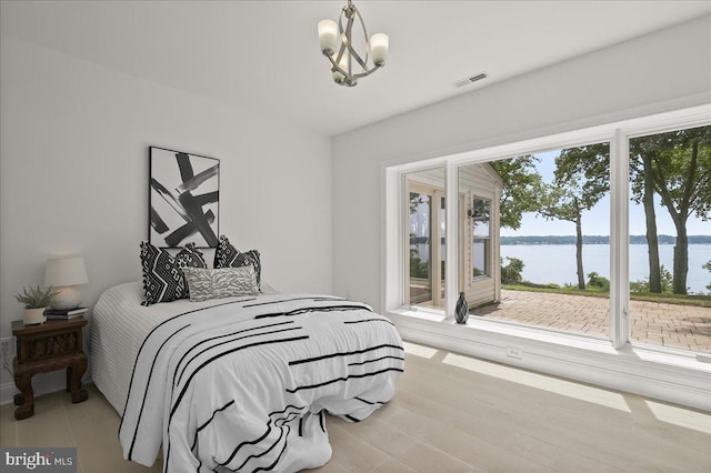 bedroom featuring visible vents, wood finished floors, a water view, access to exterior, and a chandelier