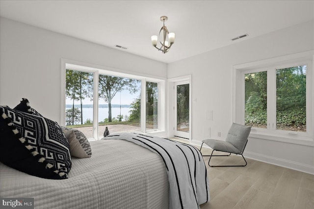 bedroom with a water view, baseboards, visible vents, and wood finished floors