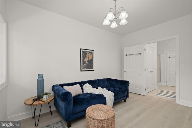 living area featuring an inviting chandelier, light wood-style flooring, and baseboards