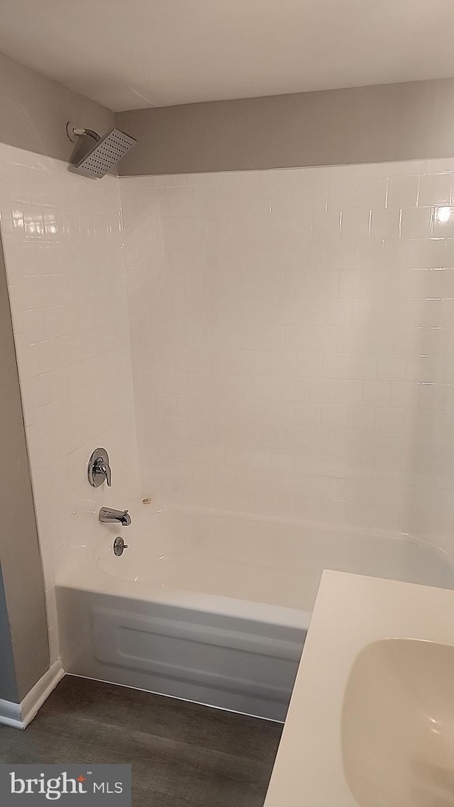 bathroom featuring  shower combination, a sink, and wood finished floors