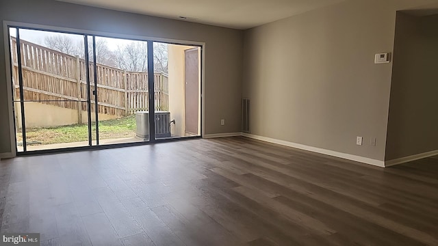 empty room featuring baseboards and dark wood-type flooring