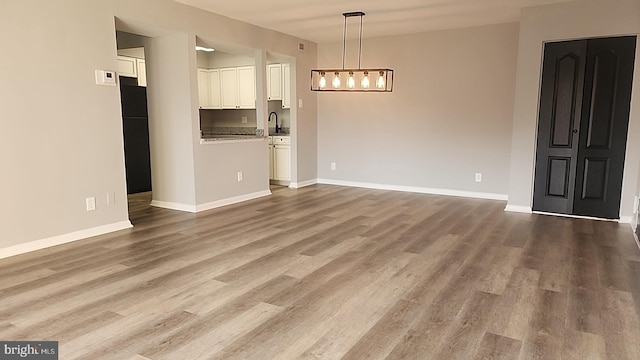 interior space featuring a sink, baseboards, and wood finished floors