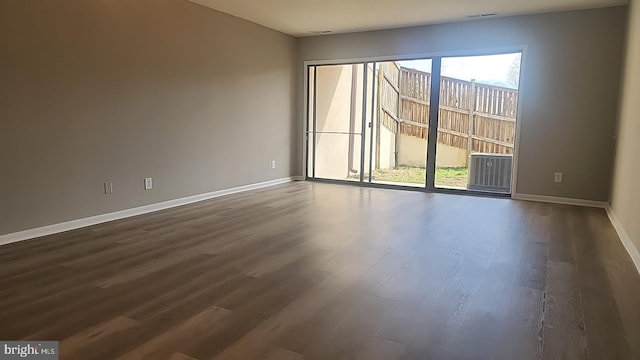 empty room featuring visible vents, baseboards, and dark wood-type flooring