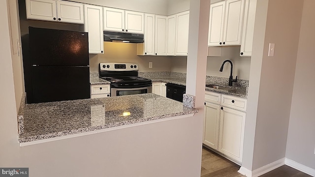 kitchen with black appliances, under cabinet range hood, stone counters, and a sink