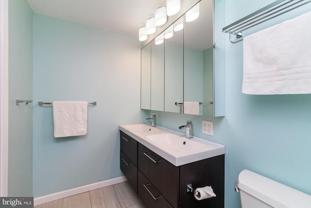 bathroom featuring toilet, vanity, and wood-type flooring