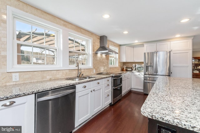 kitchen featuring sink, appliances with stainless steel finishes, wall chimney range hood, and white cabinets