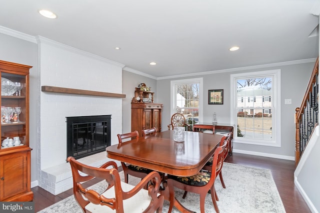 dining room with a brick fireplace, dark wood-type flooring, and ornamental molding