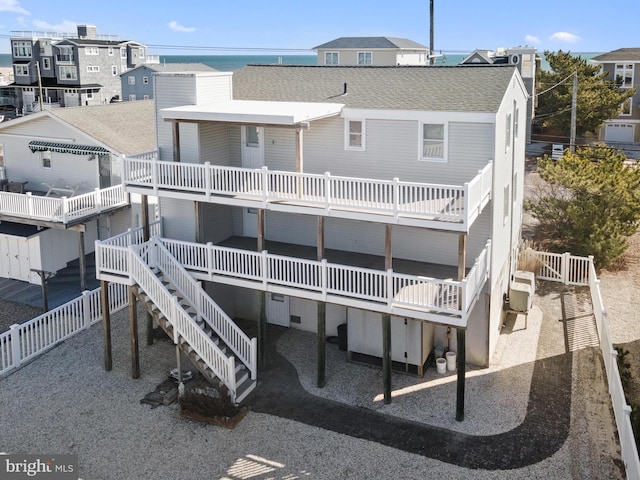 back of house featuring stairway, fence, a balcony, and a shingled roof