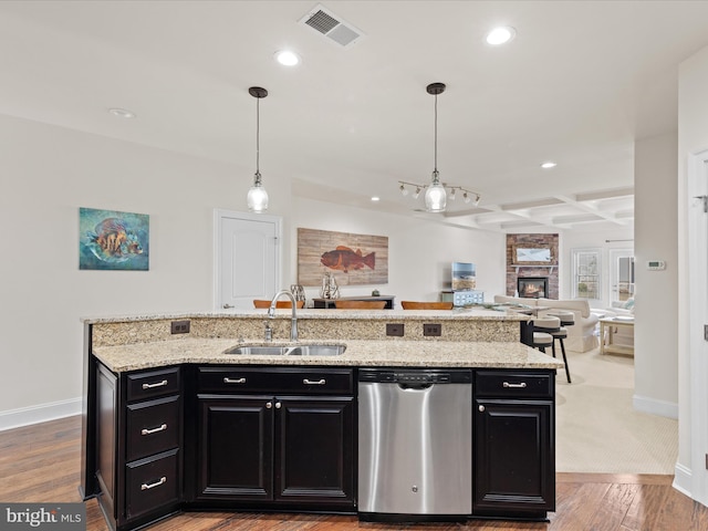 kitchen featuring visible vents, open floor plan, dark cabinets, stainless steel dishwasher, and a sink