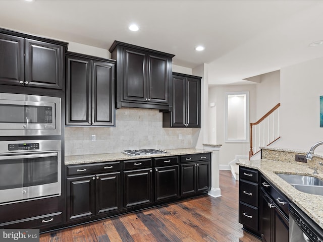 kitchen featuring appliances with stainless steel finishes, a sink, dark wood finished floors, and dark cabinets