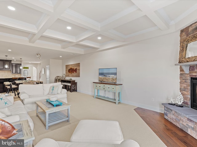 living room with beam ceiling, recessed lighting, a stone fireplace, coffered ceiling, and baseboards