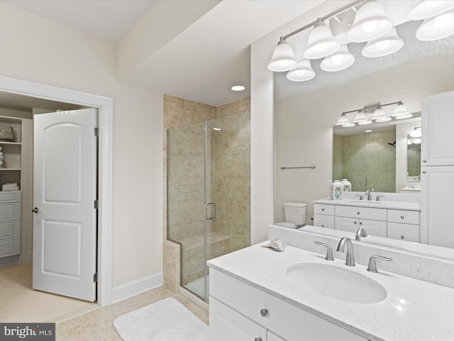 full bath featuring two vanities, a sink, a shower stall, and baseboards