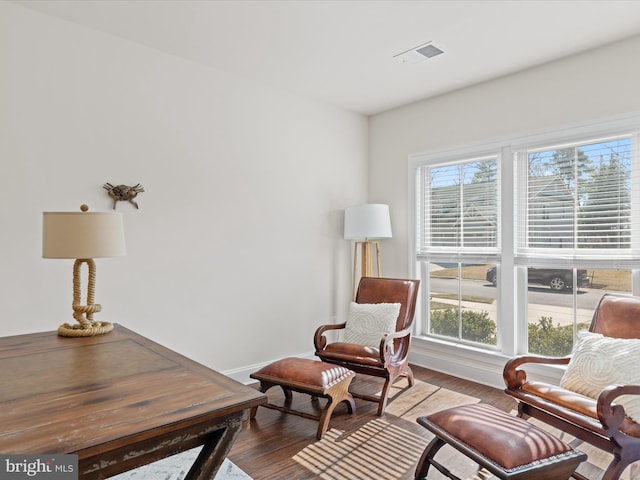 sitting room with wood finished floors, visible vents, and baseboards