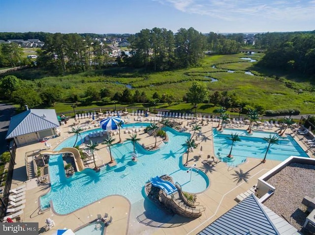 community pool with a patio area, a water slide, a water play area, and fence