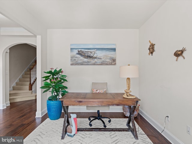 office area featuring baseboards, arched walkways, and wood finished floors