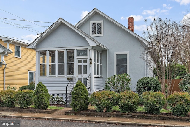 view of side of property with a sunroom, stucco siding, a chimney, and fence