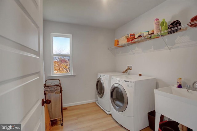 washroom featuring sink, washing machine and clothes dryer, and light hardwood / wood-style flooring