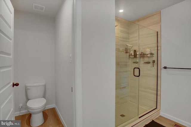 bathroom featuring toilet, hardwood / wood-style floors, and a shower with shower door