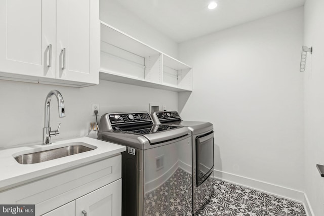 clothes washing area with sink, cabinets, and washer and dryer