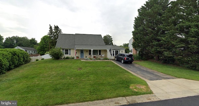 view of front of property with covered porch, aphalt driveway, a front yard, and fence