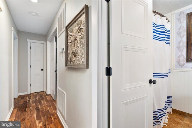 corridor with dark wood finished floors, baseboards, and visible vents
