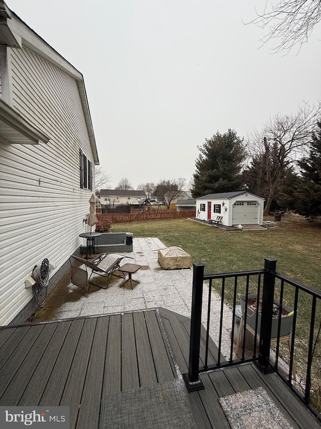 wooden terrace featuring a garage, an outdoor structure, and a yard