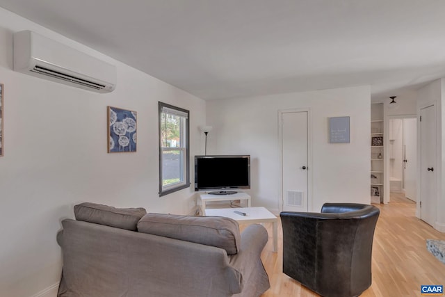 living room with a wall mounted air conditioner and light hardwood / wood-style flooring