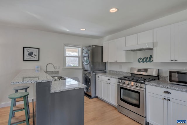 kitchen featuring white cabinetry, appliances with stainless steel finishes, stacked washer / drying machine, and sink