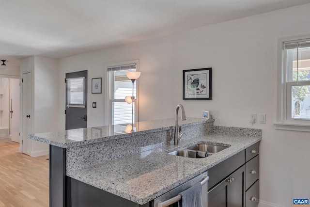 kitchen featuring sink, light stone counters, stainless steel dishwasher, kitchen peninsula, and light wood-type flooring