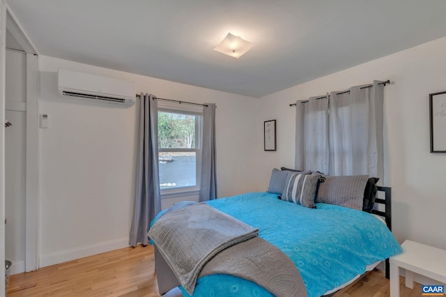 bedroom with light hardwood / wood-style floors and an AC wall unit