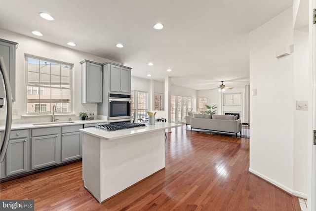 kitchen featuring hardwood / wood-style floors, light countertops, stainless steel appliances, gray cabinetry, and a sink