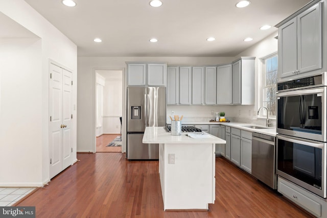 kitchen featuring gray cabinets, dark wood-style flooring, stainless steel appliances, and a sink