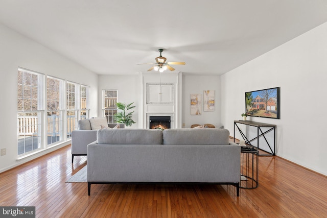 living area with hardwood / wood-style flooring, ceiling fan, and a fireplace