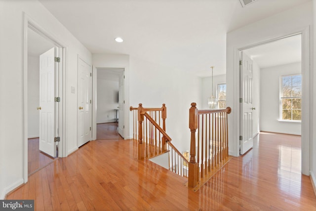 hallway with light wood finished floors, recessed lighting, an upstairs landing, and baseboards