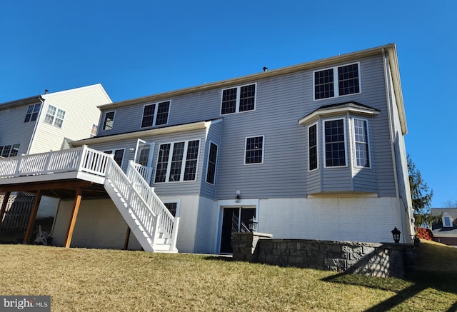 rear view of property with brick siding, a lawn, stairway, and a wooden deck