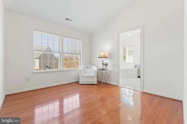 unfurnished room featuring lofted ceiling, a wealth of natural light, light wood-style flooring, and baseboards