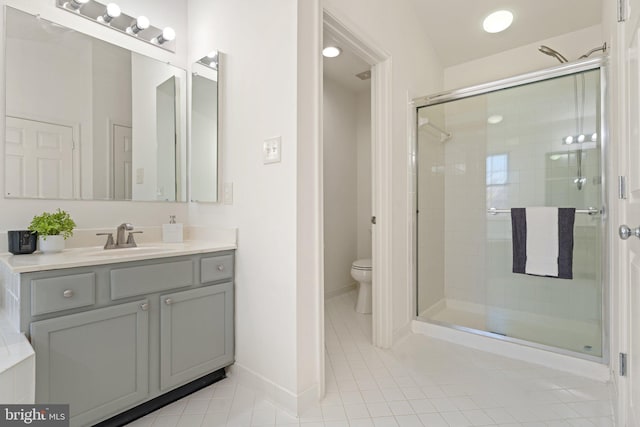 bathroom with toilet, a shower stall, vanity, tile patterned flooring, and baseboards