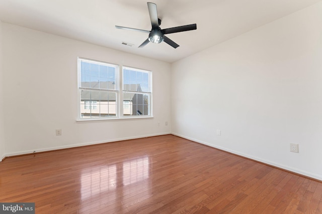 empty room with baseboards, ceiling fan, visible vents, and hardwood / wood-style floors