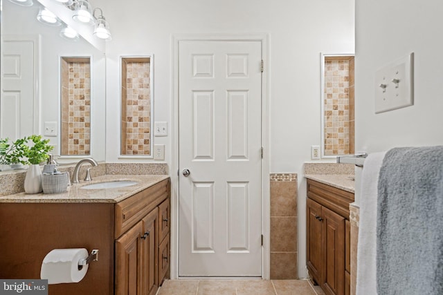 bathroom featuring two vanities, a sink, tile walls, and tile patterned floors