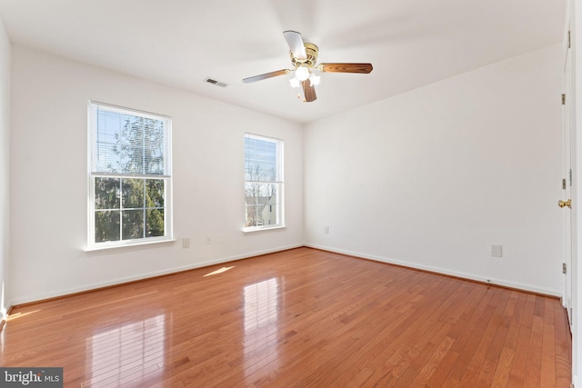 empty room with visible vents, ceiling fan, baseboards, and hardwood / wood-style flooring