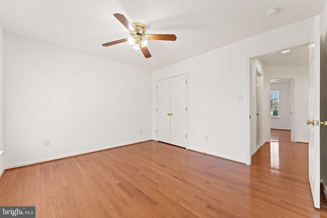 unfurnished bedroom featuring a ceiling fan, a closet, light wood-style flooring, and baseboards