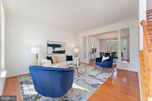 living room with a chandelier, wood finished floors, decorative columns, and crown molding