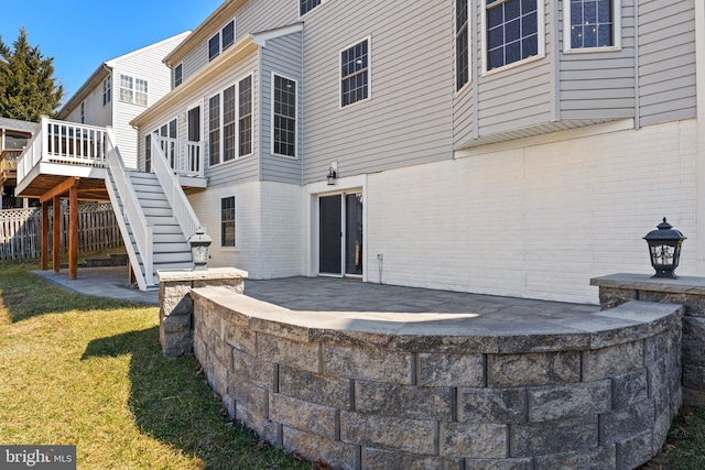 back of property with a patio area, stairs, and brick siding