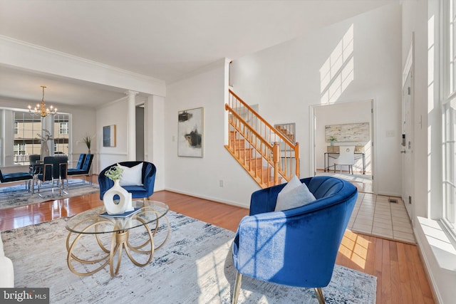 living room featuring a chandelier, wood finished floors, baseboards, stairs, and crown molding